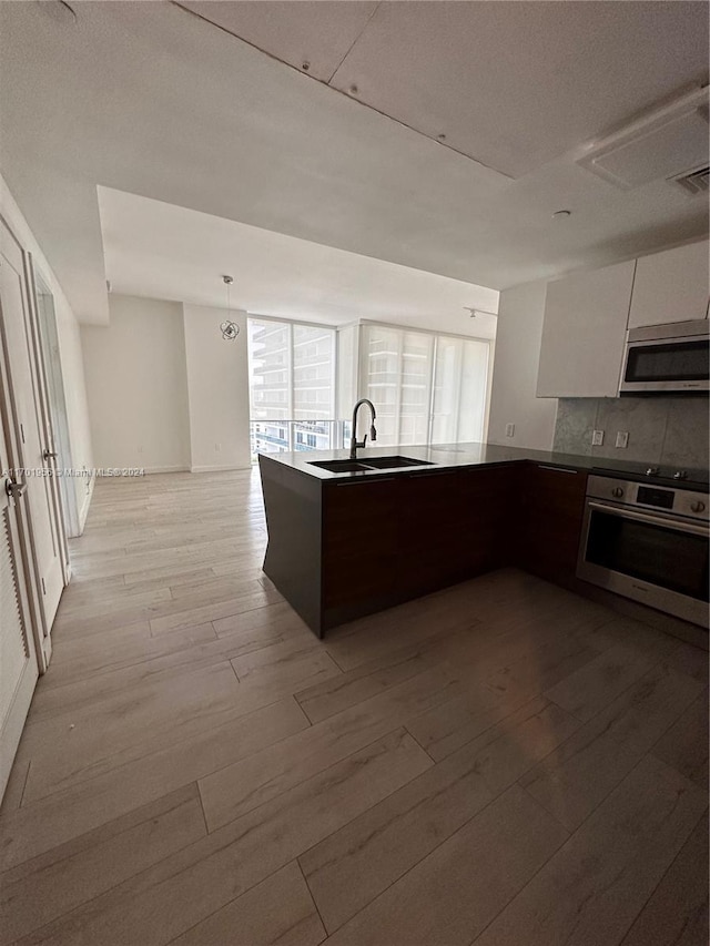 kitchen featuring white cabinets, sink, light hardwood / wood-style flooring, appliances with stainless steel finishes, and tasteful backsplash