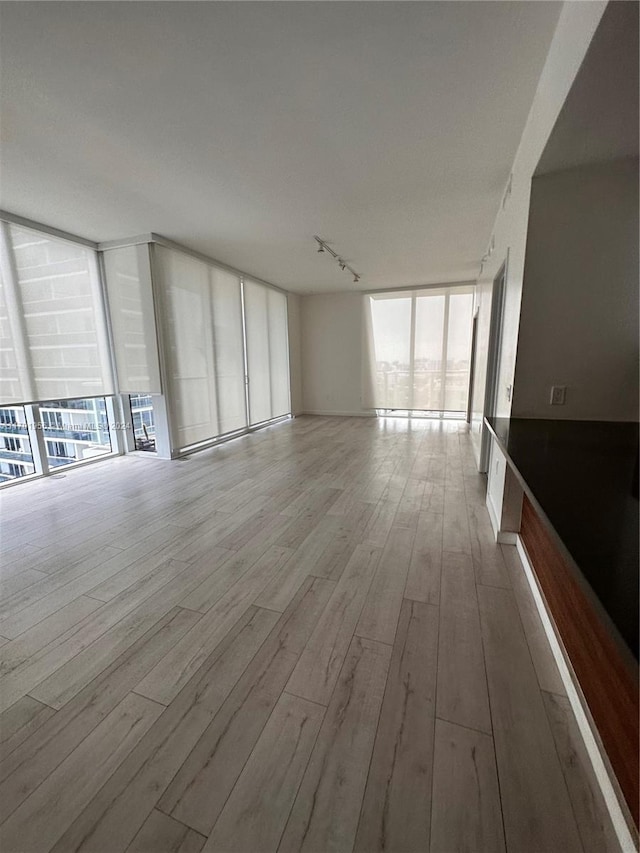 unfurnished living room with expansive windows and light hardwood / wood-style floors