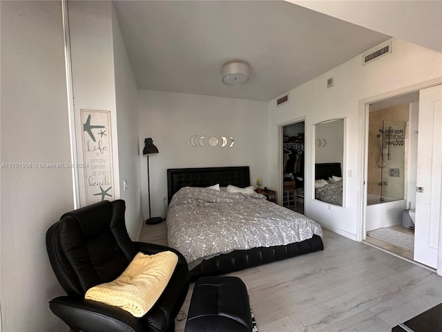 bedroom with a walk in closet, light hardwood / wood-style flooring, and a closet