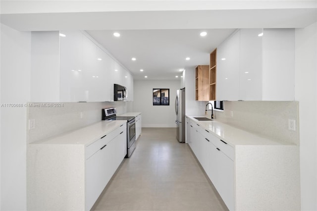 kitchen featuring white cabinets, appliances with stainless steel finishes, decorative backsplash, and sink