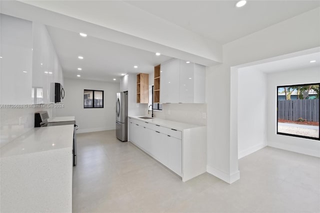 kitchen with light stone countertops, sink, stainless steel appliances, tasteful backsplash, and white cabinets