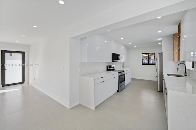 kitchen with white cabinets, sink, tasteful backsplash, light stone counters, and stainless steel appliances