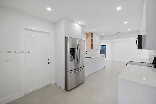 kitchen with white cabinetry, sink, tasteful backsplash, light stone counters, and appliances with stainless steel finishes