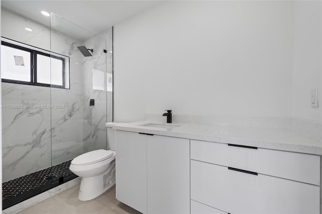 bathroom with tile patterned floors, vanity, a tile shower, and toilet