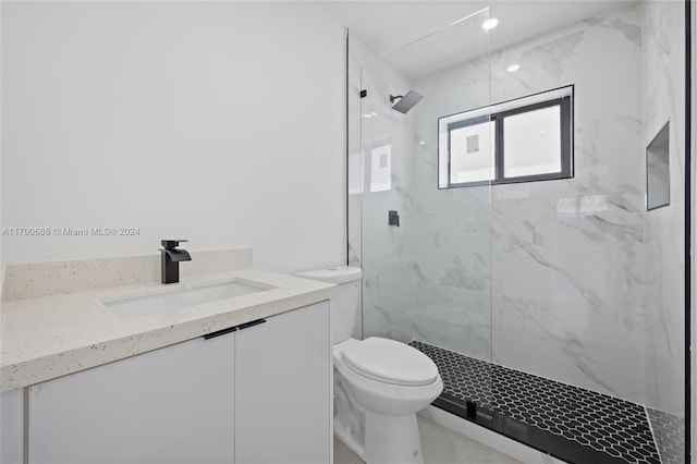 bathroom with tiled shower, vanity, and toilet