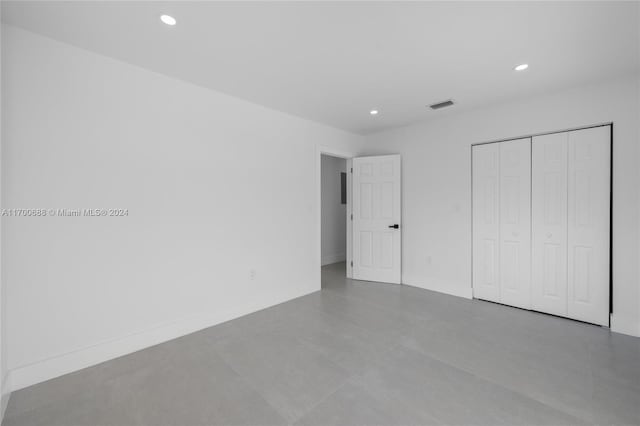 unfurnished bedroom with concrete floors and a closet