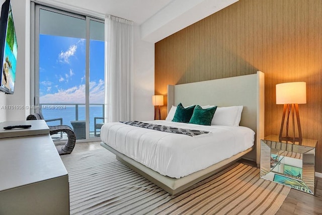 bedroom with access to outside, a water view, and light hardwood / wood-style floors