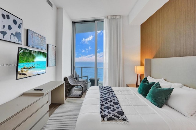 bedroom featuring access to exterior, hardwood / wood-style flooring, and expansive windows