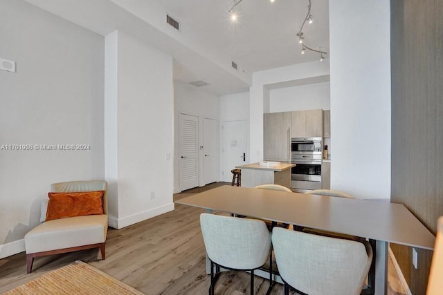 dining space featuring rail lighting and light hardwood / wood-style floors