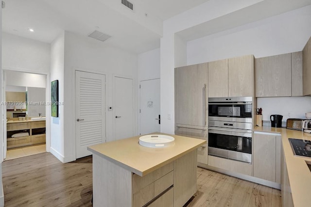 kitchen with light brown cabinets, a kitchen island, and light wood-type flooring