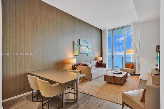 living room featuring a water view, a wall of windows, and light hardwood / wood-style flooring