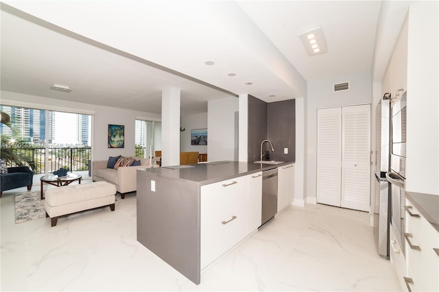 kitchen featuring stainless steel dishwasher, kitchen peninsula, white cabinetry, and sink