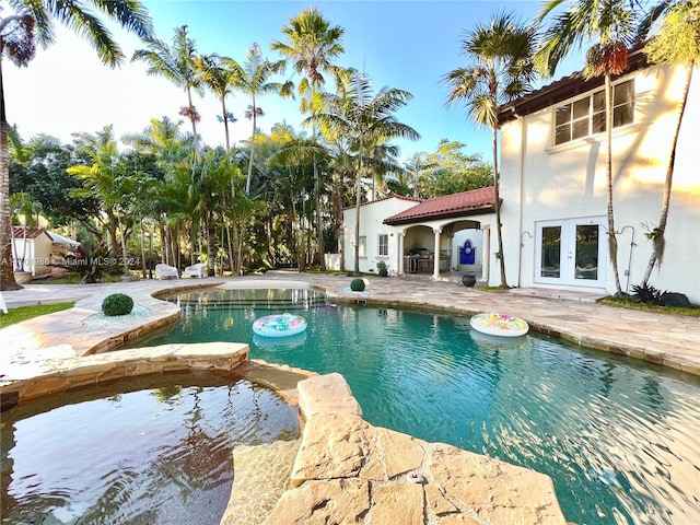 view of swimming pool featuring an in ground hot tub and french doors