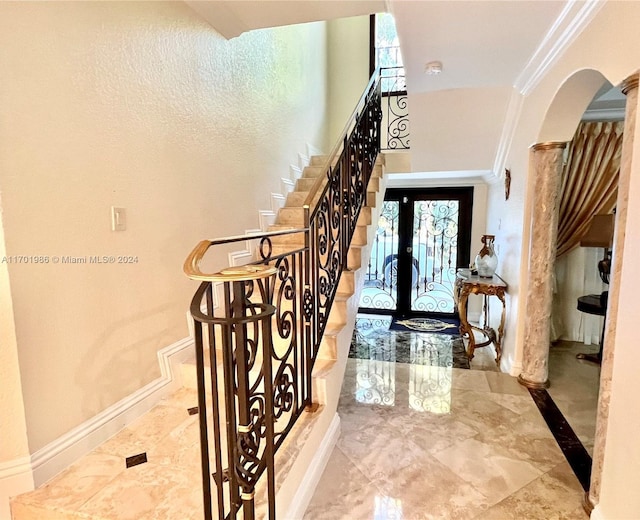 entryway with ornamental molding and french doors