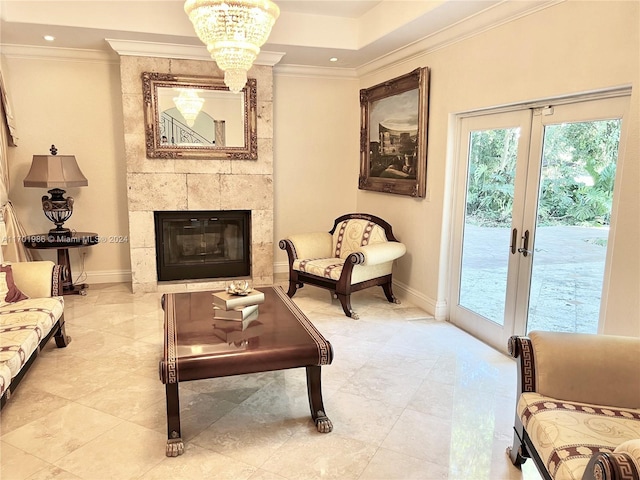 living area with a tile fireplace, french doors, an inviting chandelier, and crown molding