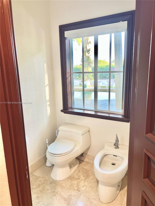 bathroom with tile patterned flooring, toilet, and a bidet