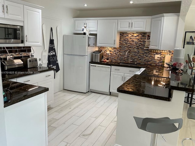 kitchen featuring backsplash, sink, white cabinets, and white appliances