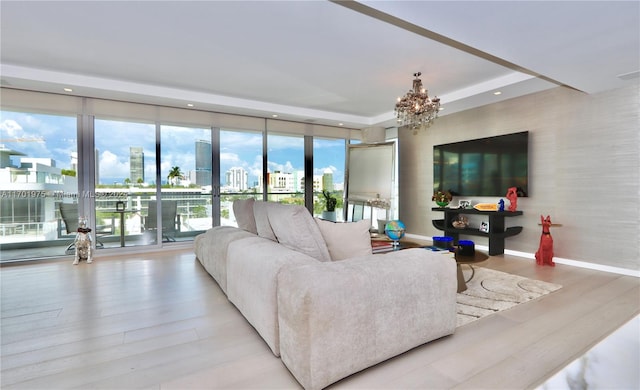 living room with a raised ceiling, a chandelier, and light hardwood / wood-style floors