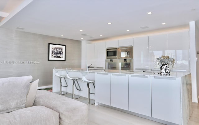 kitchen with white cabinets, stainless steel appliances, a spacious island, and sink