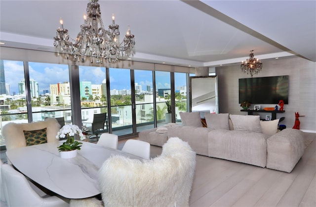 living room with a raised ceiling, a notable chandelier, and light wood-type flooring