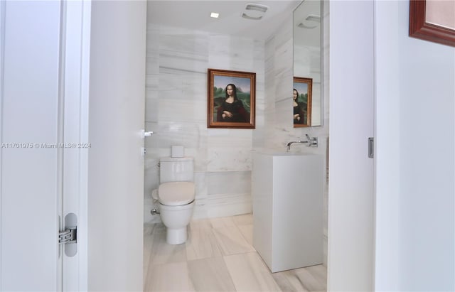 bathroom with toilet and tile walls