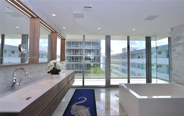 bathroom featuring decorative backsplash, vanity, a bath, and a wall of windows