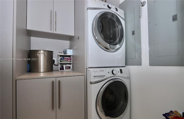 laundry room with electric panel and stacked washing maching and dryer