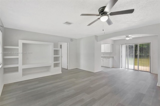 1101 SW Addie St, Port St Lucie, FL 34983 - unfurnished living room with a ceiling fan, light wood-type flooring, a textured ceiling, and arched walkways