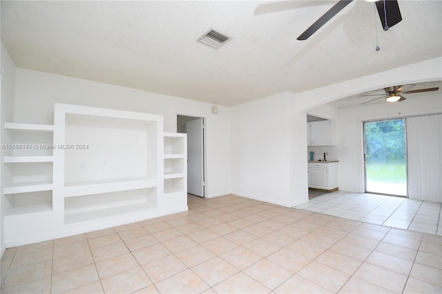 unfurnished living room featuring light tile patterned floors, a textured ceiling, built in features, and ceiling fan