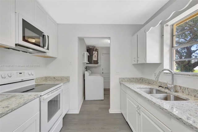 1101 SW Addie St, Port St Lucie, FL 34983 - kitchen featuring white appliances, light wood-style floors, white cabinets, and washer and dryer