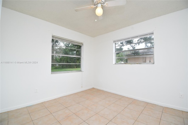 empty room featuring ceiling fan, light tile patterned floors, and a healthy amount of sunlight