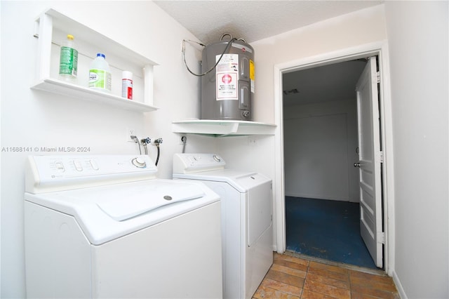 clothes washing area featuring washing machine and clothes dryer, water heater, and a textured ceiling