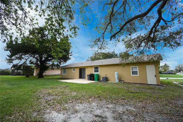 rear view of property featuring a yard, a patio, and central AC