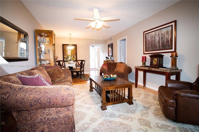 living area featuring visible vents, baseboards, ceiling fan, and light wood finished floors