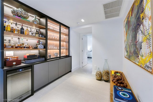 bar with visible vents, a dry bar, beverage cooler, and light carpet