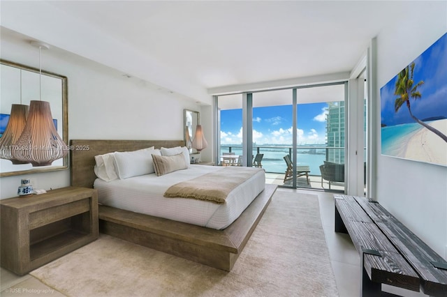 bedroom with access to exterior, a water view, and floor to ceiling windows