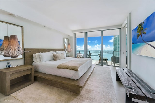 bedroom featuring access to outside, floor to ceiling windows, and a water view