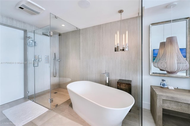 bathroom with a shower stall, a freestanding tub, tile walls, and tile patterned floors