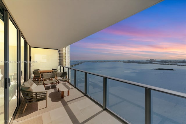 balcony at dusk featuring a water view