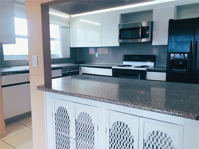 kitchen with decorative backsplash, light tile patterned floors, black appliances, dark stone countertops, and white cabinetry