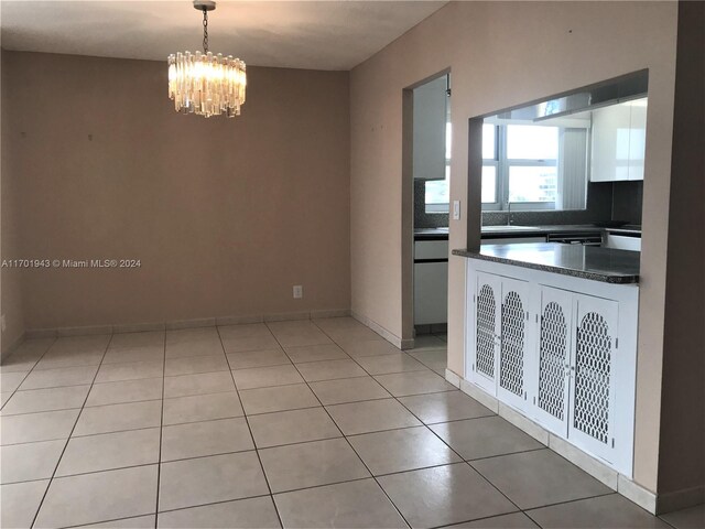 interior space featuring sink, decorative backsplash, decorative light fixtures, light tile patterned flooring, and a chandelier