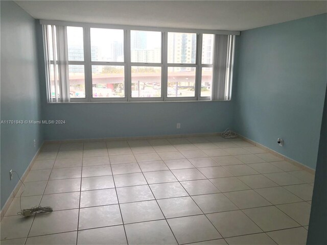 spare room with a wealth of natural light and light tile patterned flooring