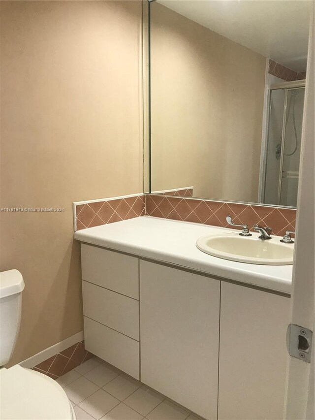 bathroom featuring backsplash, tile patterned floors, vanity, a shower with door, and toilet