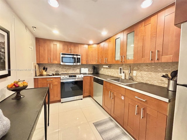 kitchen featuring backsplash, light tile patterned floors, sink, and appliances with stainless steel finishes