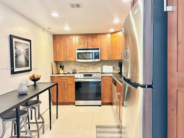 kitchen with decorative backsplash, stainless steel appliances, and light tile patterned flooring