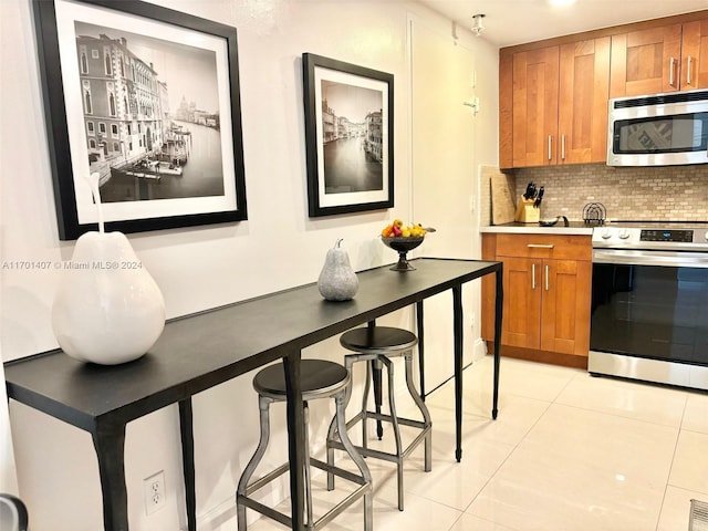 kitchen featuring stainless steel appliances, tasteful backsplash, a breakfast bar area, and light tile patterned flooring