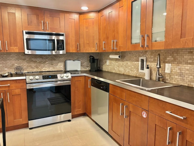 kitchen with decorative backsplash, appliances with stainless steel finishes, light tile patterned floors, and sink