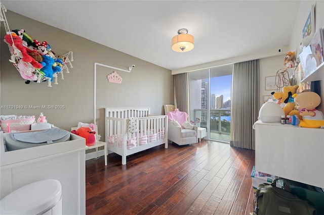 bedroom featuring floor to ceiling windows, dark hardwood / wood-style floors, and a nursery area