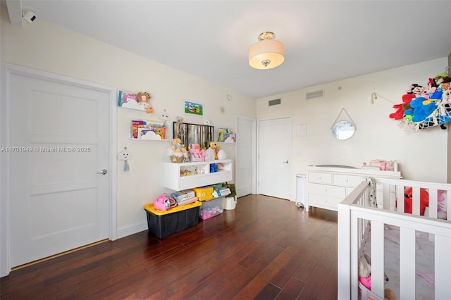 bedroom with a crib and dark hardwood / wood-style floors