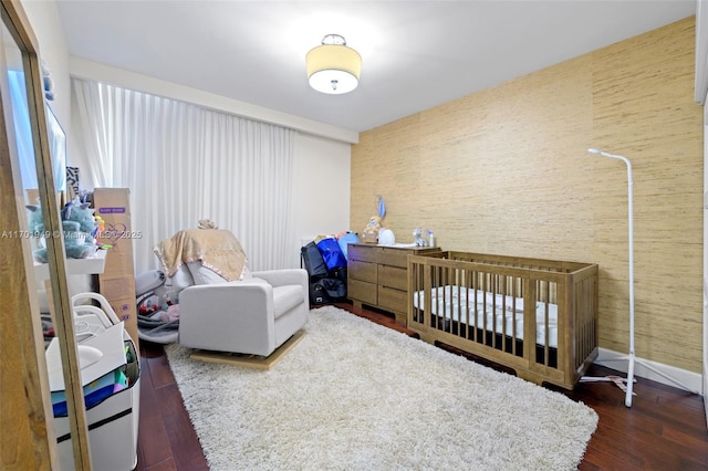 bedroom featuring dark hardwood / wood-style flooring and a nursery area